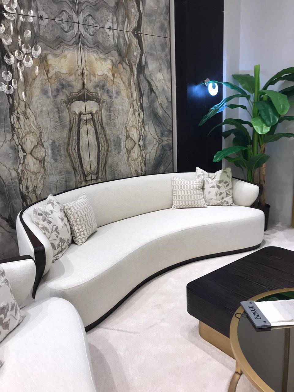 Calm luxury living and dining furniture collection with curved upholstered sofas, dark wood dining table, and elegant sideboard cabinetry.