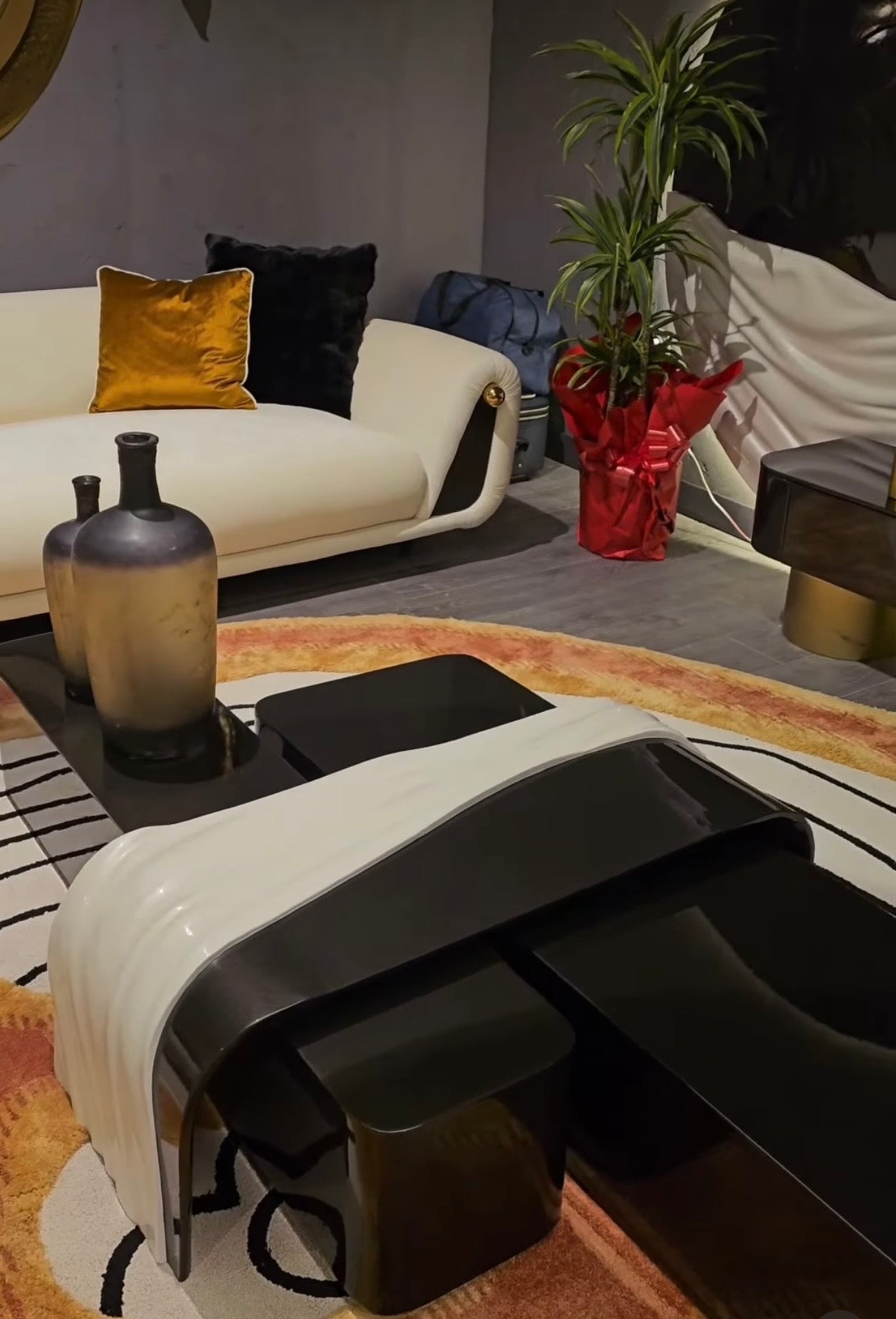 Monochrome modern luxury furniture collection featuring ivory curved sofa, black lacquer tables, and gold accent dining furniture.