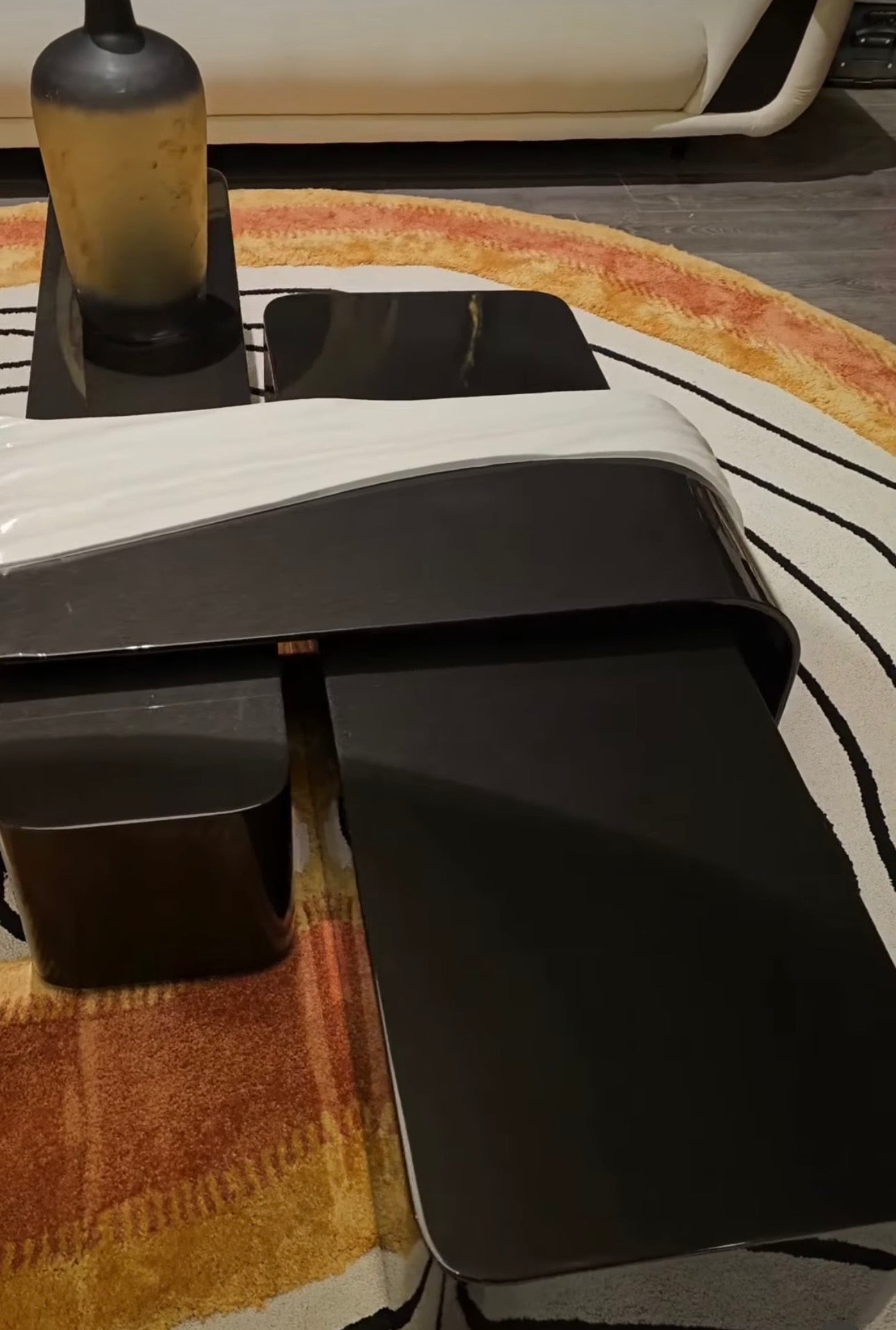 Monochrome modern luxury furniture collection featuring ivory curved sofa, black lacquer tables, and gold accent dining furniture.