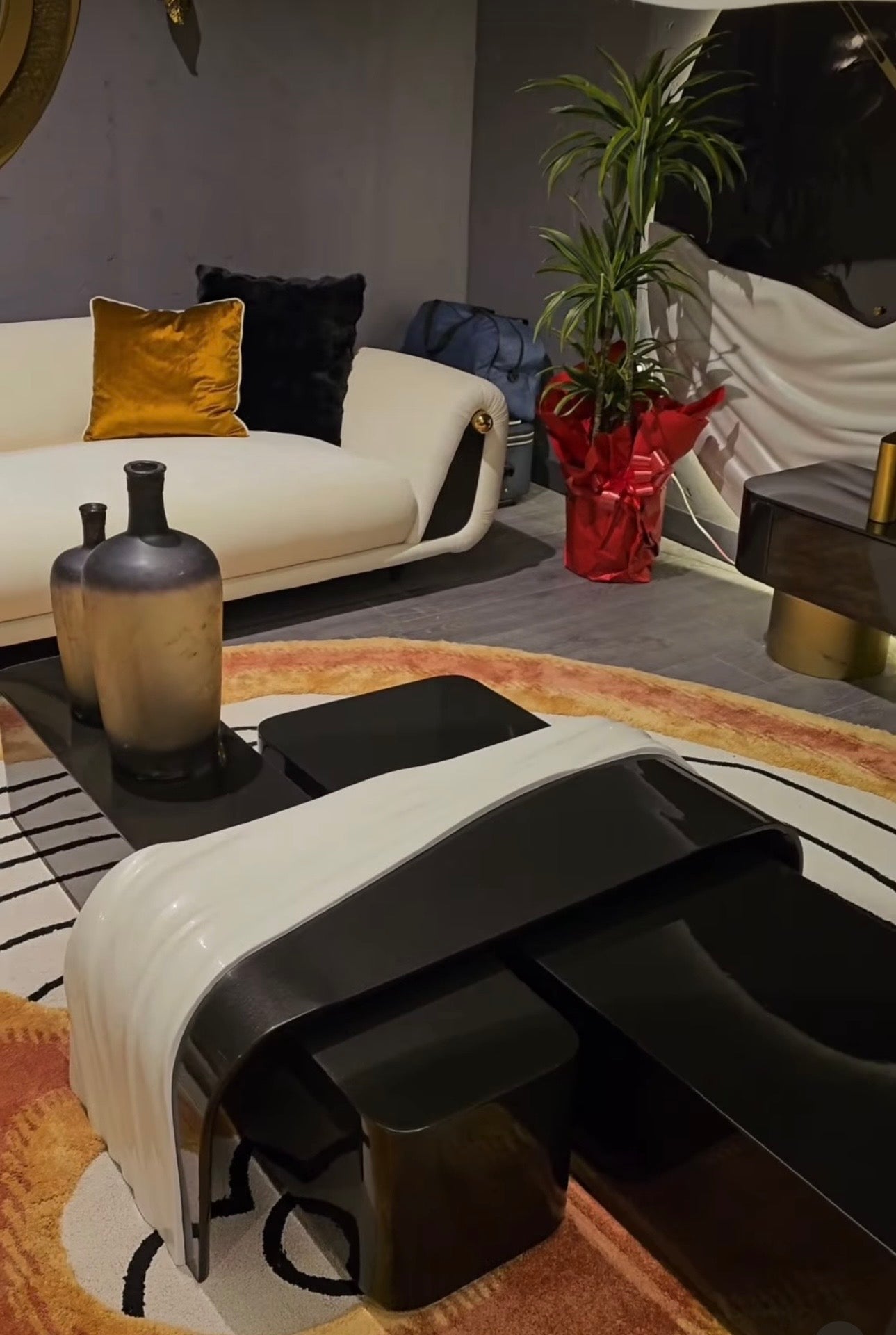 Monochrome modern luxury furniture collection featuring ivory curved sofa, black lacquer tables, and gold accent dining furniture.