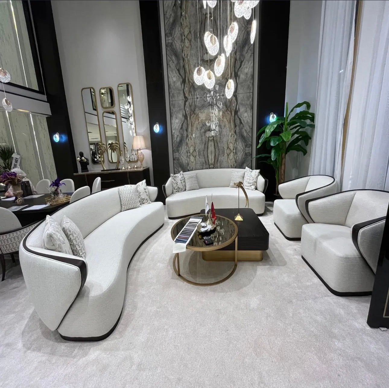 Calm luxury living and dining furniture collection with curved upholstered sofas, dark wood dining table, and elegant sideboard cabinetry.