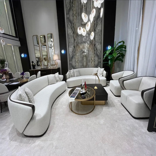Calm luxury living and dining furniture collection with curved upholstered sofas, dark wood dining table, and elegant sideboard cabinetry.