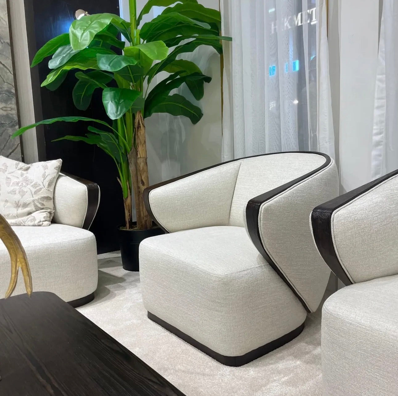 Calm luxury living and dining furniture collection with curved upholstered sofas, dark wood dining table, and elegant sideboard cabinetry.