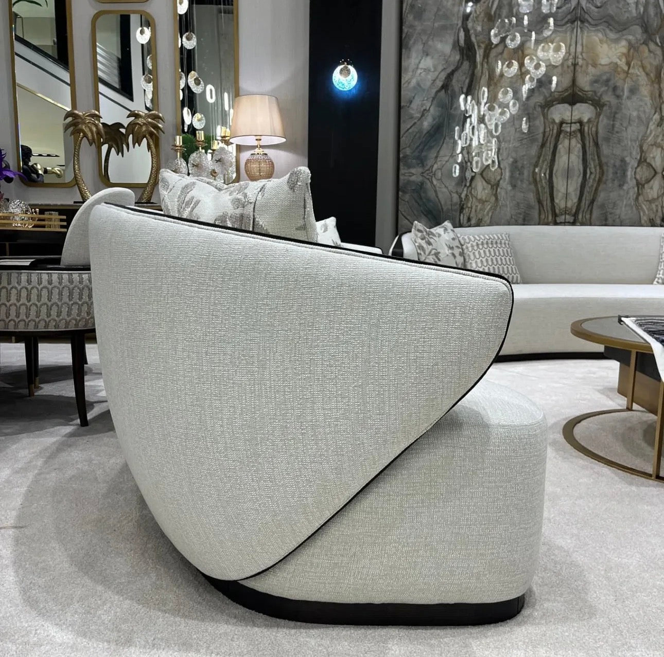 Calm luxury living and dining furniture collection with curved upholstered sofas, dark wood dining table, and elegant sideboard cabinetry.