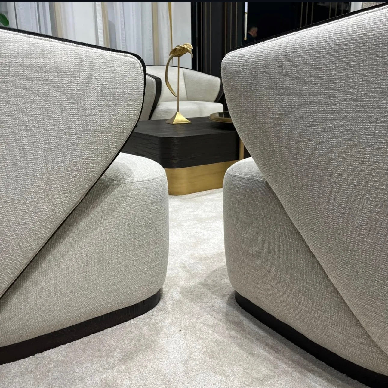 Calm luxury living and dining furniture collection with curved upholstered sofas, dark wood dining table, and elegant sideboard cabinetry.