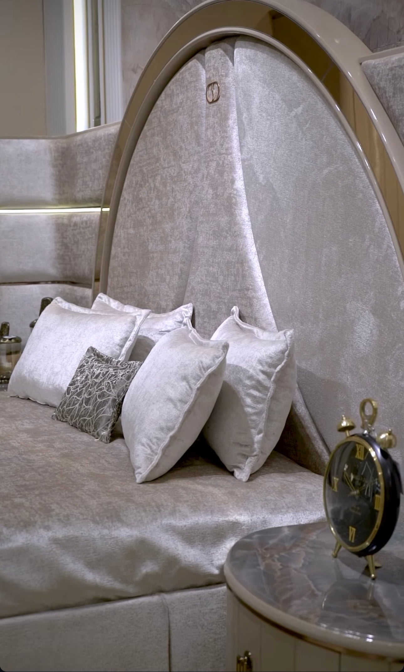 Crown luxury modern bedroom furniture collection with arched statement bed, marble dining table, mirrored wardrobe, and sculptural vanity.