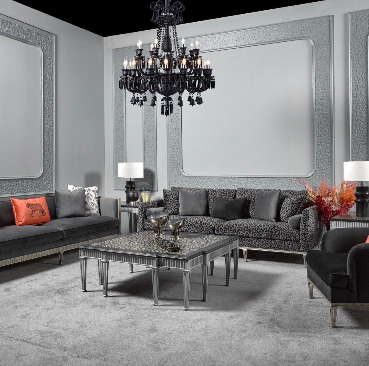 Panthera luxury furniture collection featuring statement sofa, sculptural coffee table, pedestal table, and modern shelving in dark finishes.