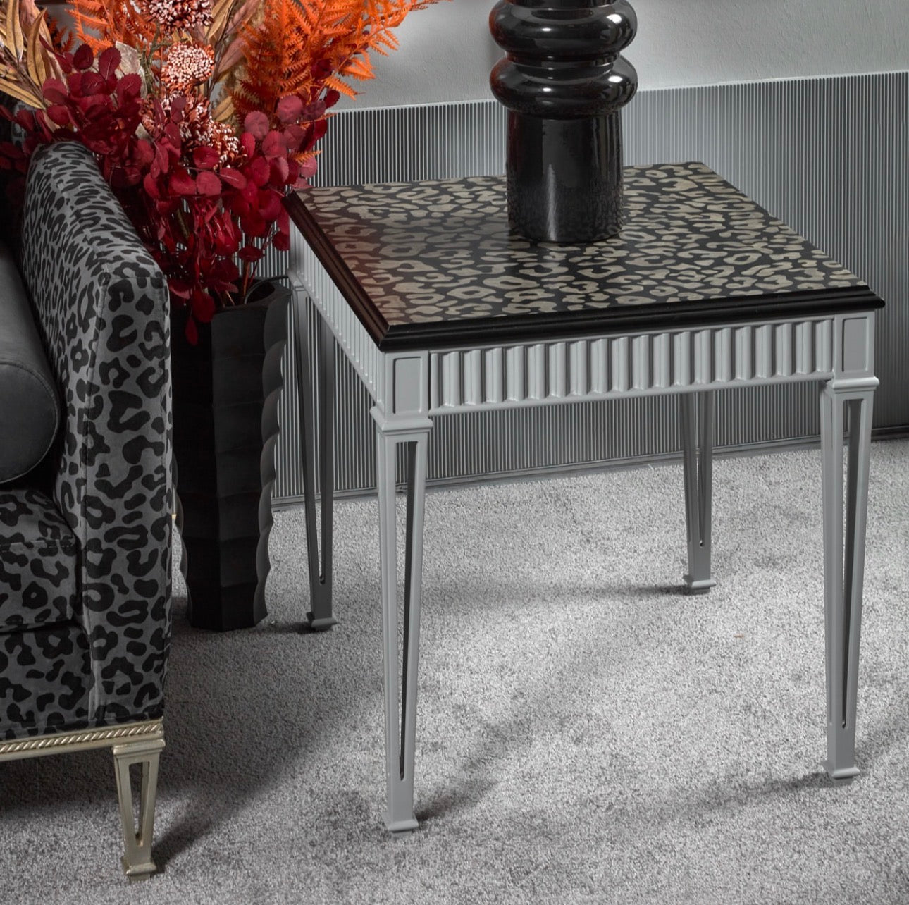 Panthera luxury furniture collection featuring statement sofa, sculptural coffee table, pedestal table, and modern shelving in dark finishes.