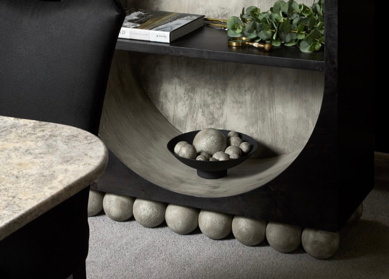 Panthera luxury furniture collection featuring statement sofa, sculptural coffee table, pedestal table, and modern shelving in dark finishes.