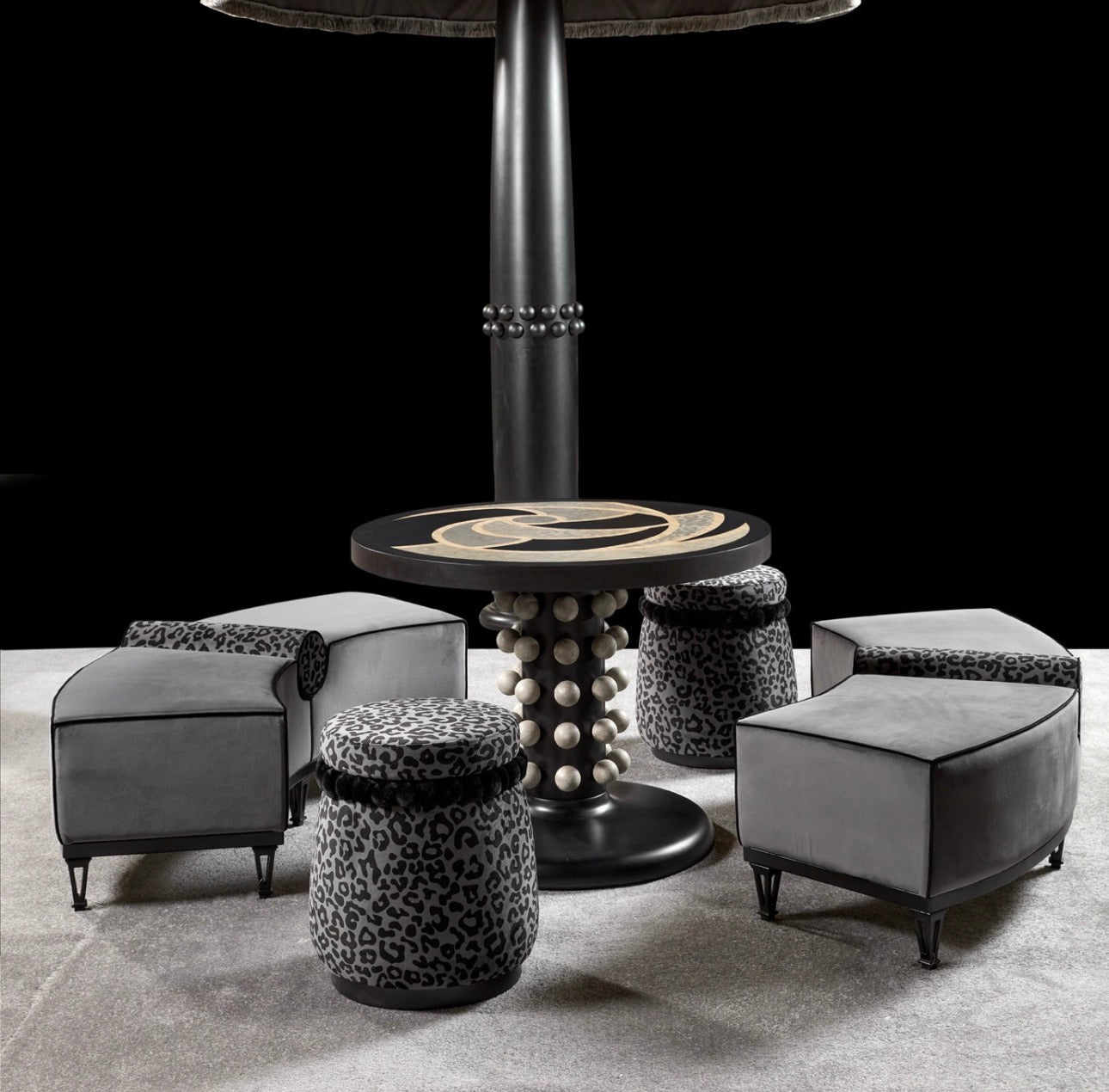 Panthera luxury furniture collection featuring statement sofa, sculptural coffee table, pedestal table, and modern shelving in dark finishes.