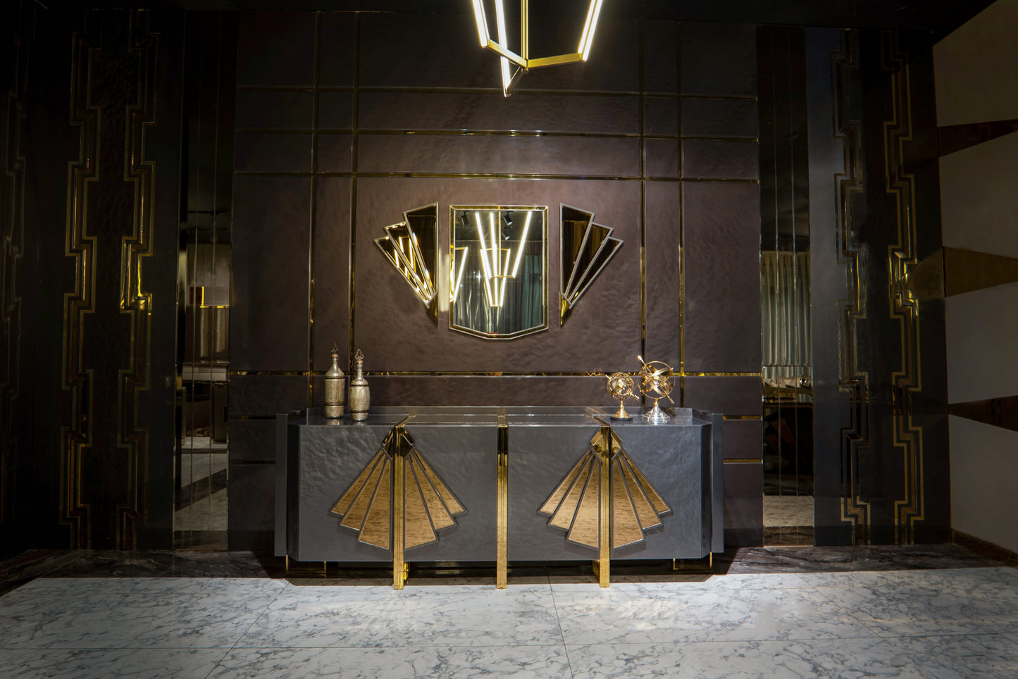 Frost luxury furniture collection featuring geometric wall mirror, dark lacquer sideboard with gold accents, and patterned armchairs with sculptural brass frames.