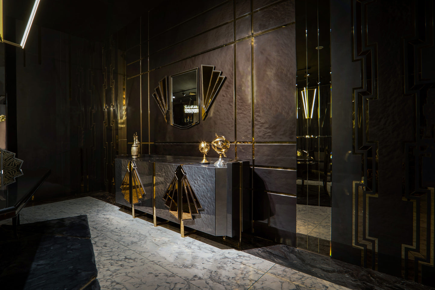 Frost luxury furniture collection featuring geometric wall mirror, dark lacquer sideboard with gold accents, and patterned armchairs with sculptural brass frames.