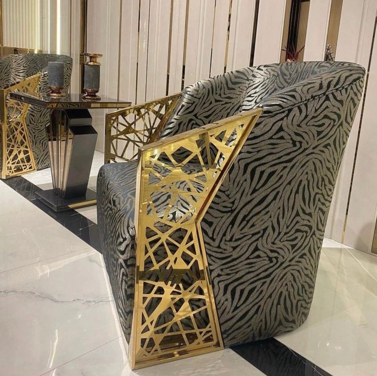 Frost luxury furniture collection featuring geometric wall mirror, dark lacquer sideboard with gold accents, and patterned armchairs with sculptural brass frames.