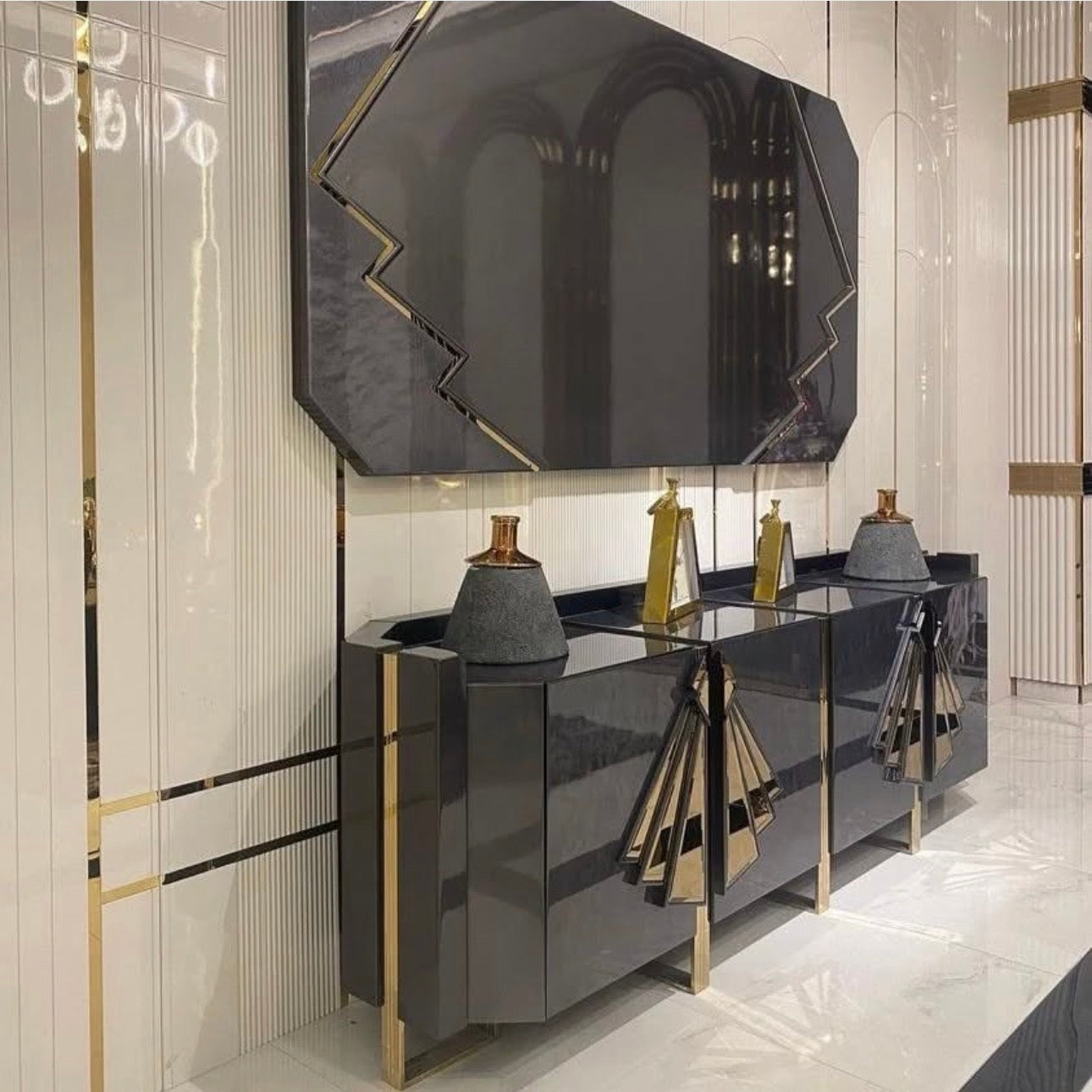 Frost luxury furniture collection featuring geometric wall mirror, dark lacquer sideboard with gold accents, and patterned armchairs with sculptural brass frames.
