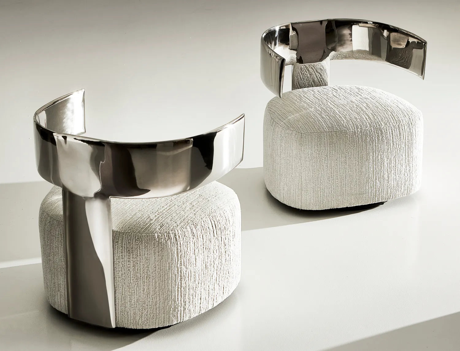 Orvane chairs with curved polished metal backs and textured upholstered bases in a modern luxury setting.